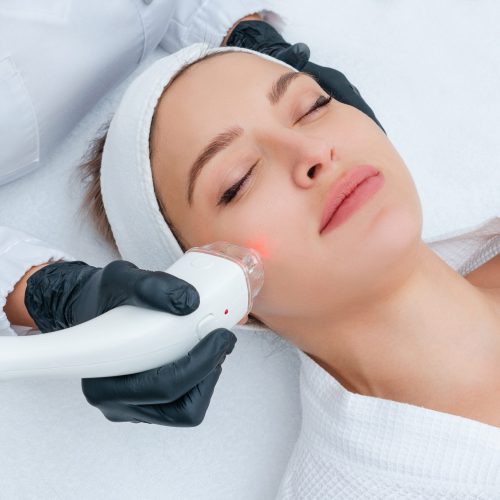 Young woman receiving laser treatment in cosmetology clinic Young woman receiving laser treatment